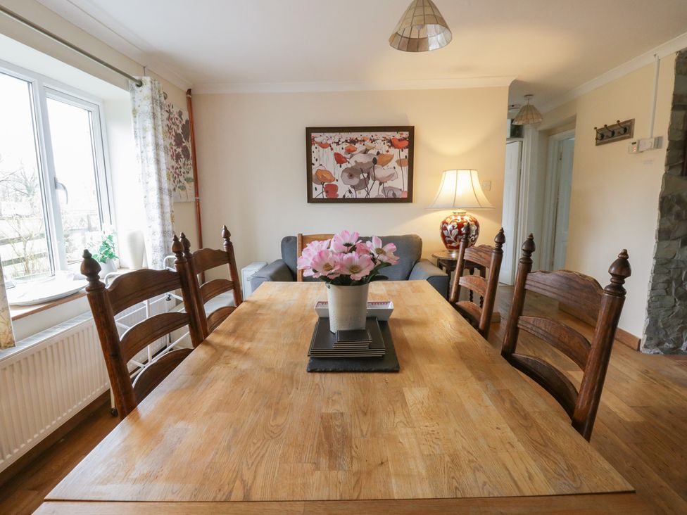 A dining room with a wooden table and chairs at Glanyrafon Smithy in New Quay