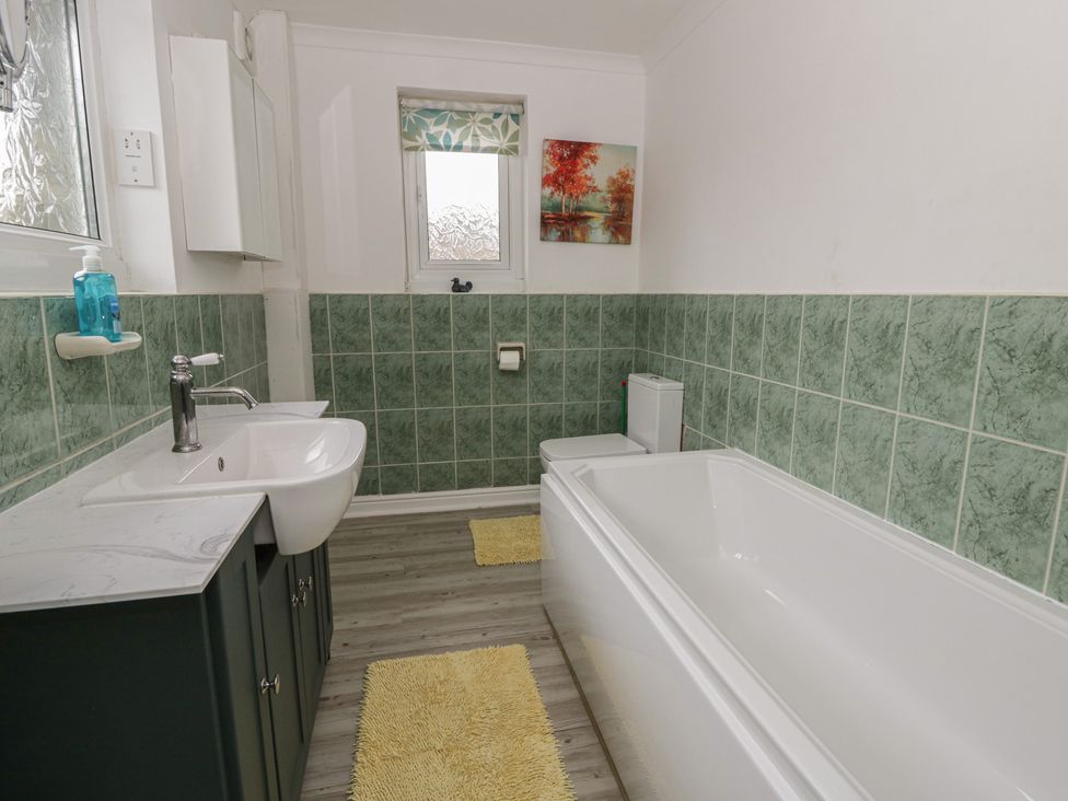 A bathroom with a bathtub, sink, and toilet at Glanyrafon Smithy in New Quay