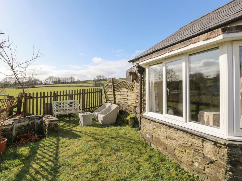 A garden with seating and a fence at Glanyrafon Smithy in New Quay