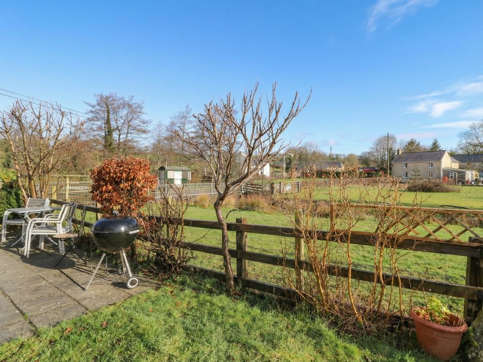 A garden with chairs and a barbecue grill at Glanyrafon Smithy in New Quay