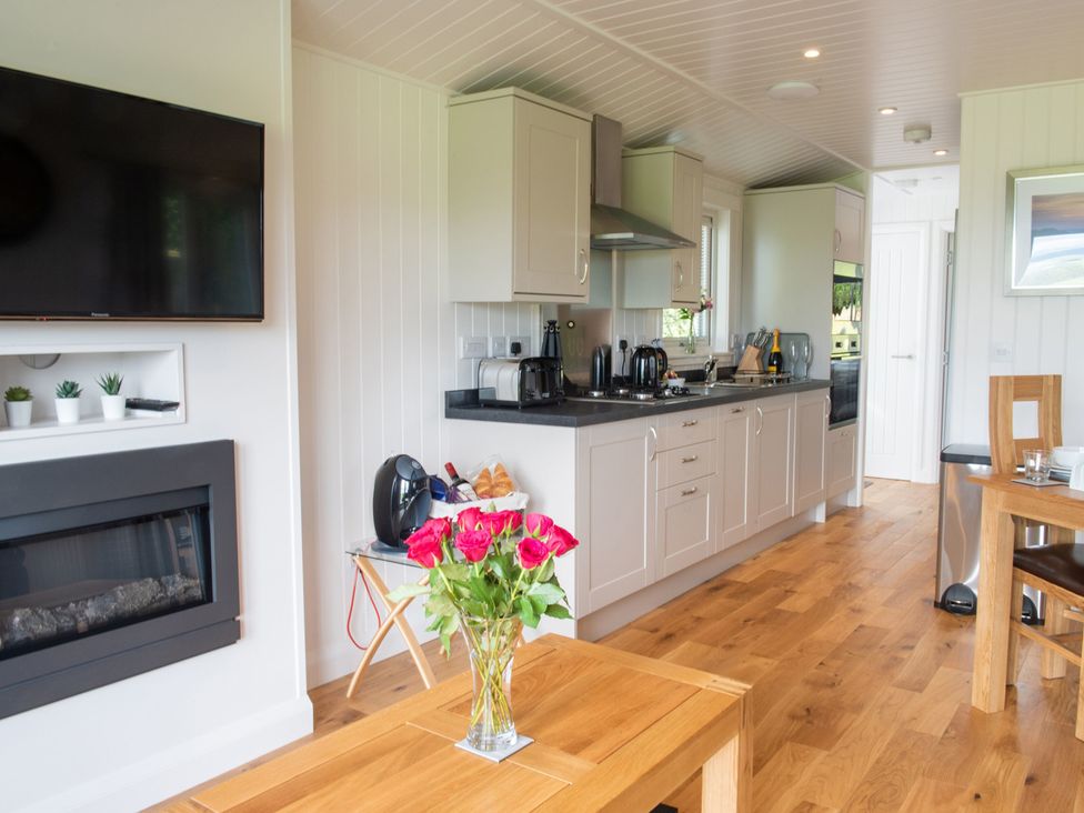 A kitchen with cabinets and a vase of flowers at Nethermill Lodges in Port Glasgow