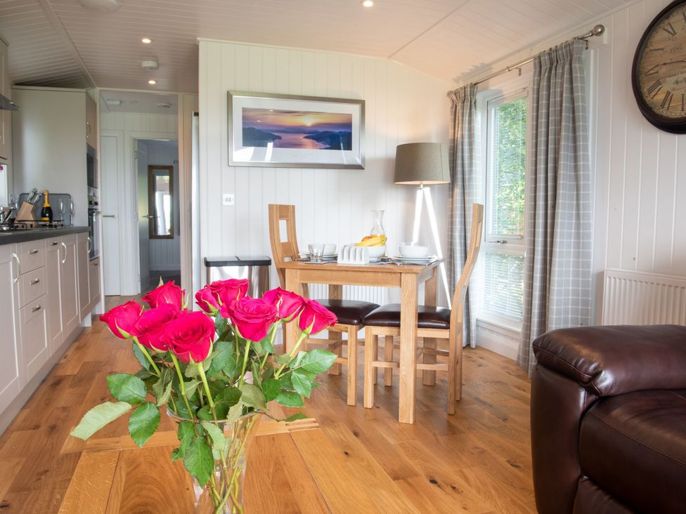 A dining room with a table, chairs, and flowers at Nethermill Lodges Port Glasgow