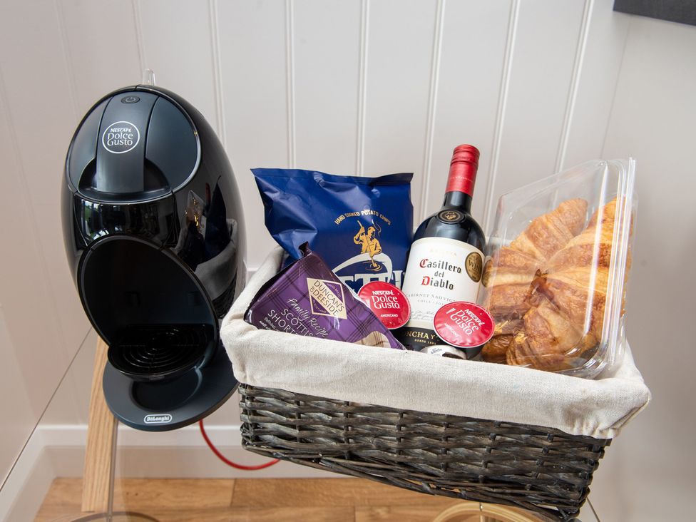 A coffee machine with snacks and drinks in a basket at Nethermill Lodges in Port Glasgow