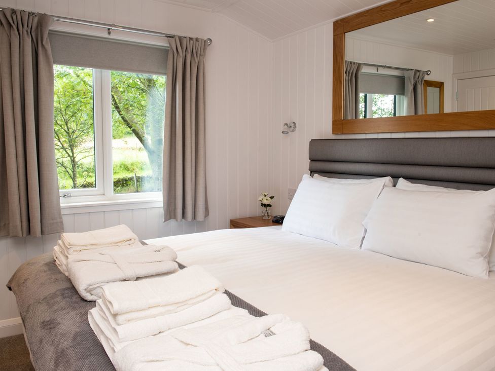 A bedroom with a bed and window at Nethermill Lodges in Port Glasgow