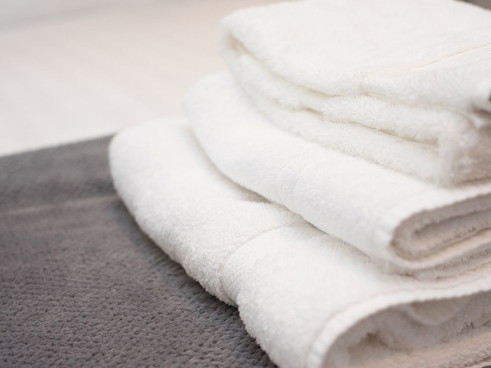 A stack of white towels on a gray bath rug at Nethermill Lodges in Port Glasgow