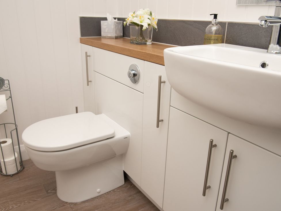 A bathroom with a toilet, sink, and cabinetry at Nethermill Lodges in Port Glasgow