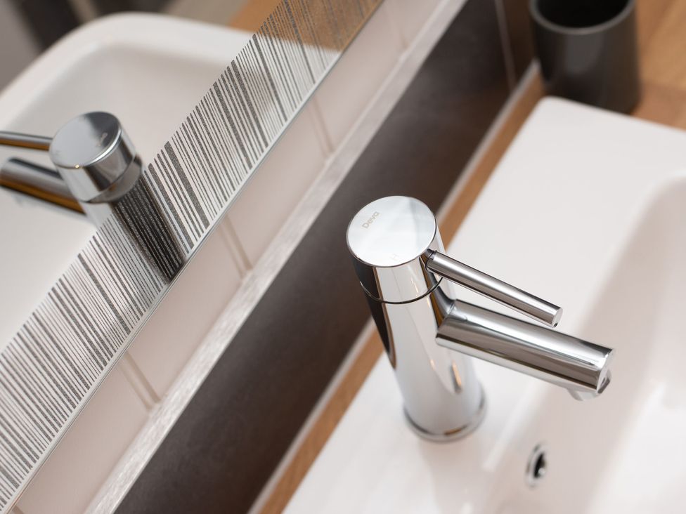 A sink and faucet with a mirror in a bathroom at Nethermill Lodges in Port Glasgow