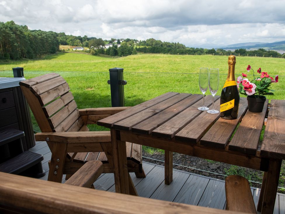 A table with chairs and champagne on a balcony at Nethermill Lodges in Port Glasgow