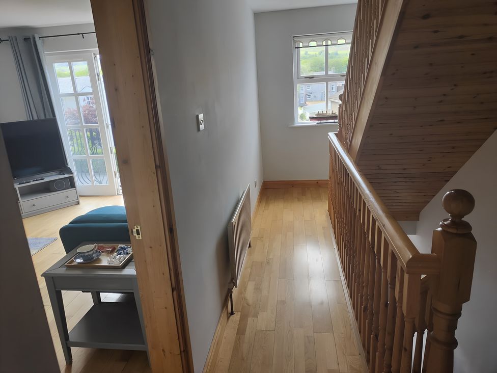 A hallway with a staircase and a view of a living room at 17 Castleview Ballymena