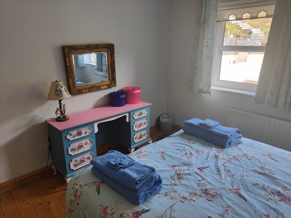 A bedroom with a desk, bed, towels, lamp, and mirror at 17 Castleview in Ballymena