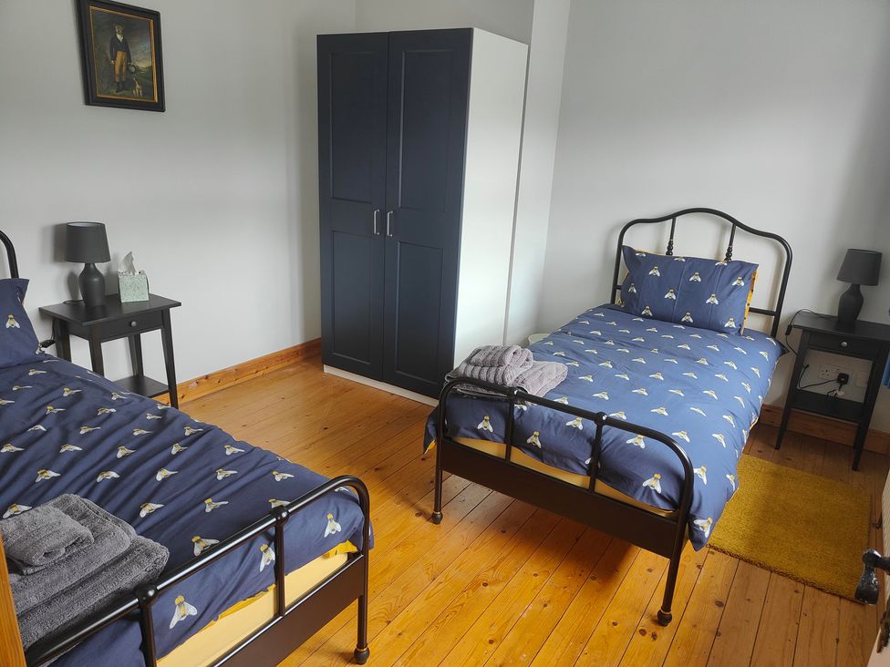 A bedroom with two beds, wardrobe and nightstand at 17 Castleview in Ballymena