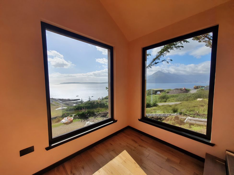 A room with large windows overlooking water at Cullinview in Isle of Skye