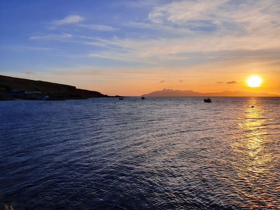 A view of the sea at sunset with boats and mountains at Cullinview in Isle of Skye
