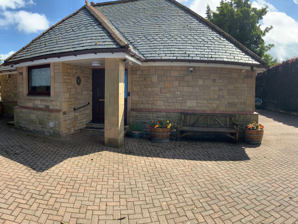 A house with a brick pathway and flower pots at Fenton Drive Wooler