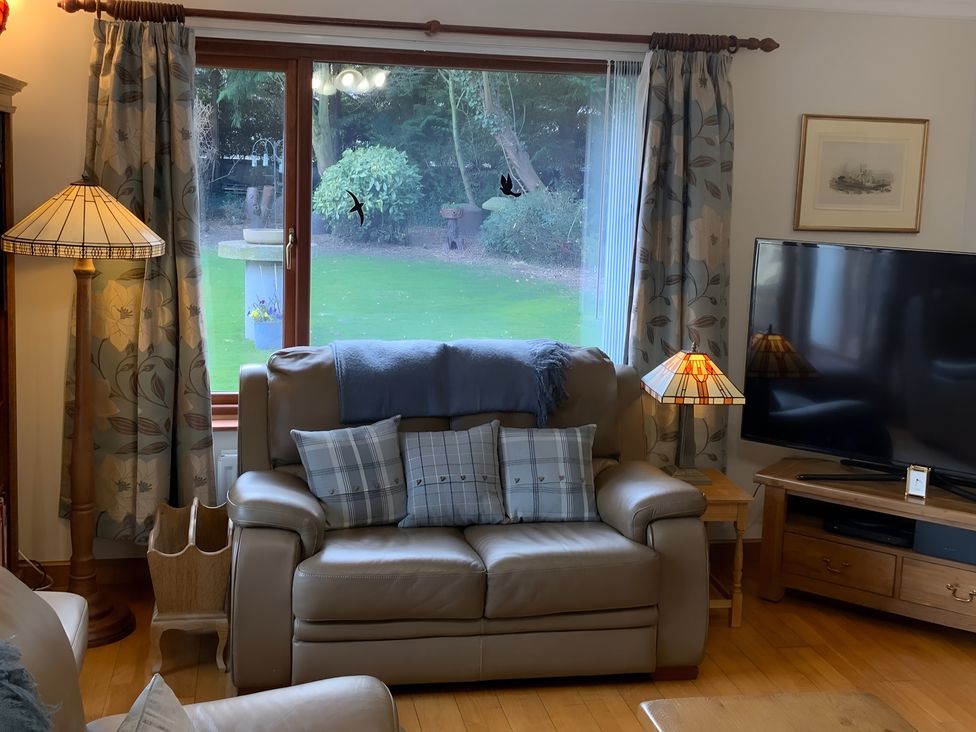 A living room with a sofa, cushions, and television at Fenton Drive in Wooler