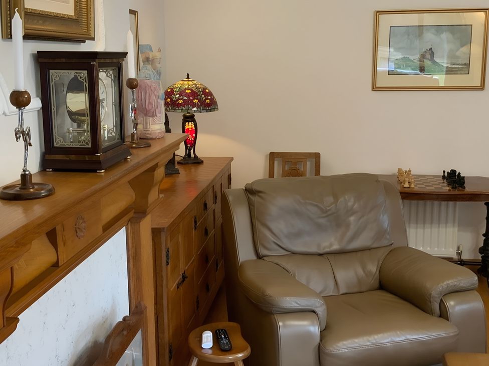 A living room with a chair, lamp, and clock at Fenton Drive in Wooler