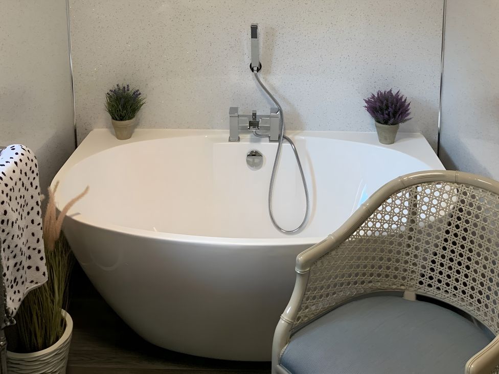 A bathroom with a bathtub and chair at Fenton Drive Wooler