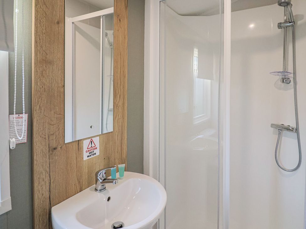 A bathroom with a sink, mirror, and shower at WF32 - Jurassic Discovery in Charmouth