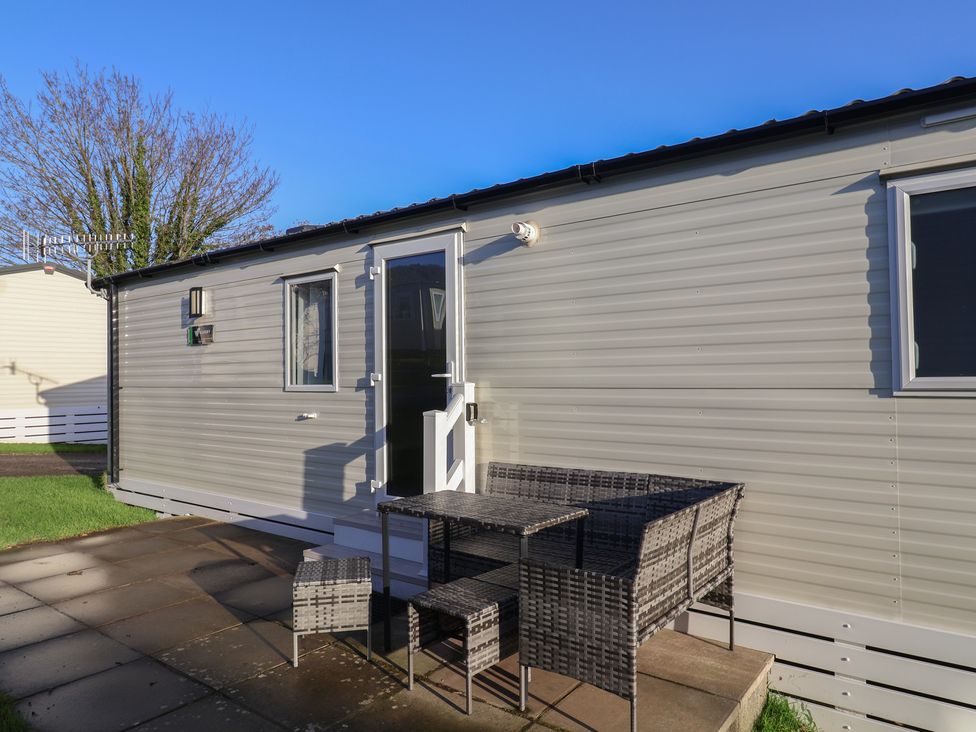 An exterior view of a mobile home with a table and chairs at Jurassic Discovery in Charmouth