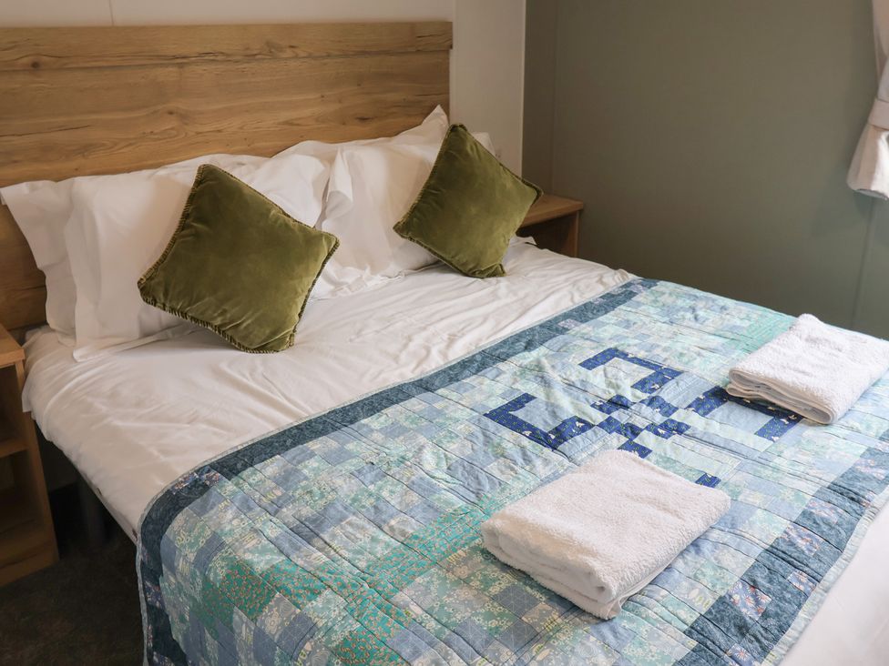 A bedroom with a bed, pillows, towels, and a quilt at Jurassic Discovery in Charmouth