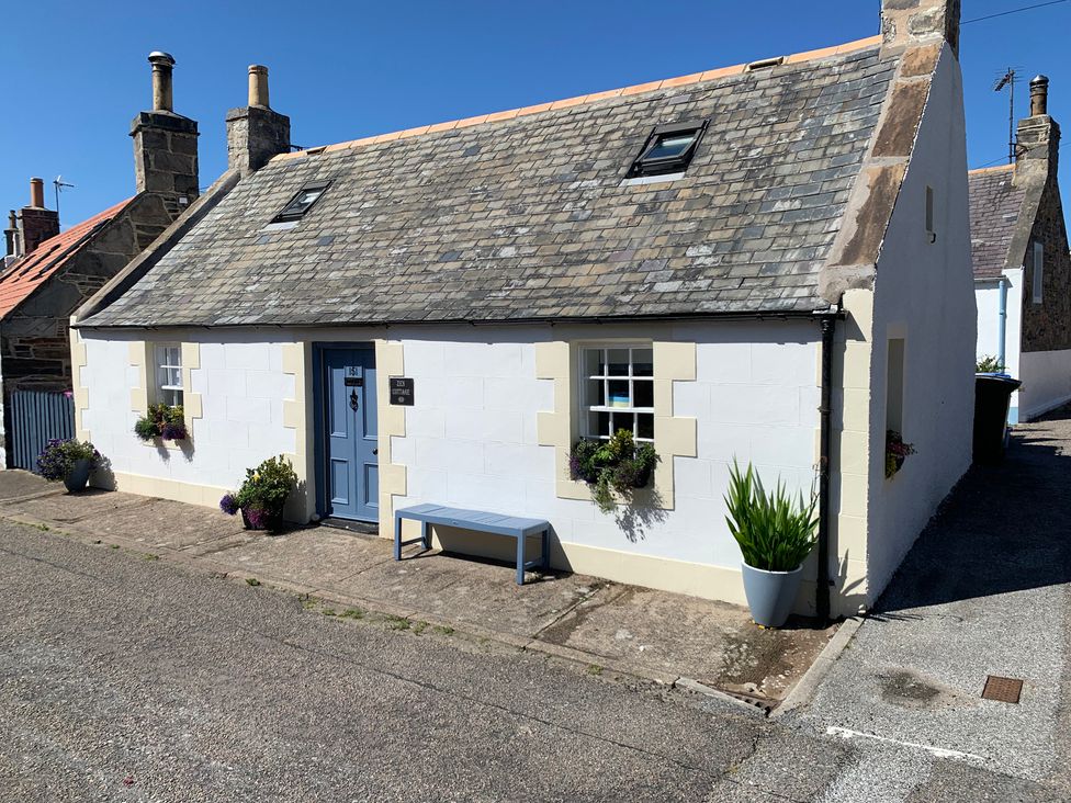 An exterior view of a house with a blue door and planters at Zen Cottage in Buckie
