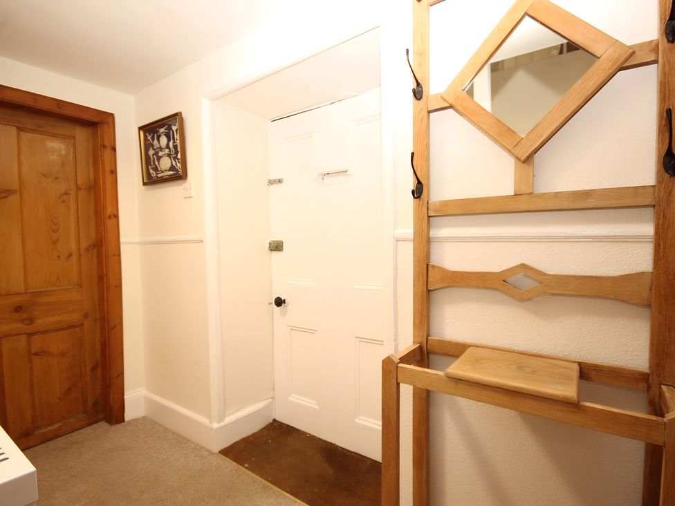 A hallway with a wooden rack and a mirror at Zen Cottage in Buckie