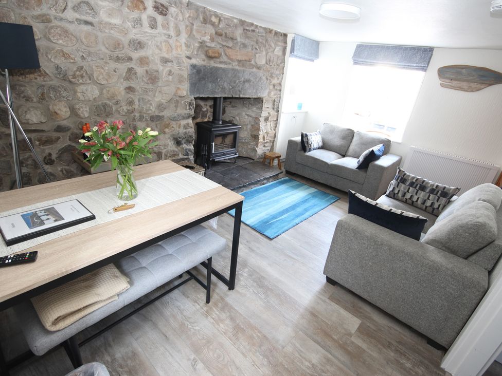 A living room with a wood stove and seating at Zen Cottage in Buckie