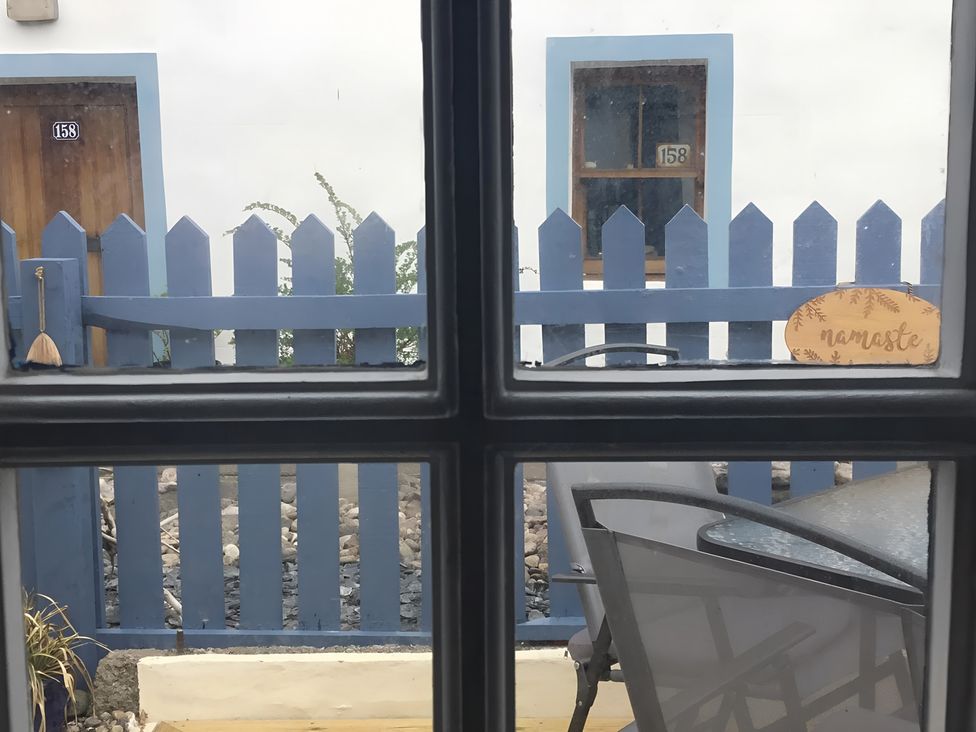 An outdoor area with a blue fence, door, table, and chair at Zen Cottage in Buckie