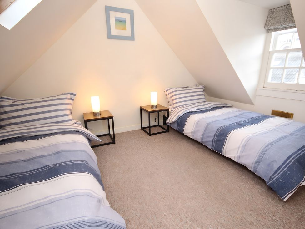A bedroom with two beds and bedside tables at Zen Cottage in Buckie