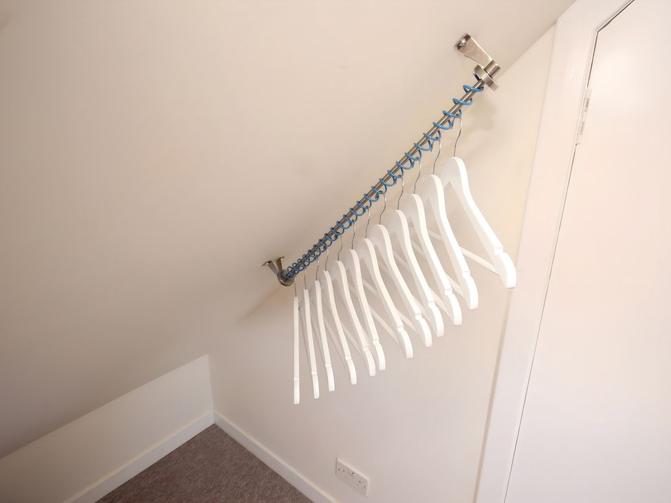 A storage room with hanging clothes hangers at Zen Cottage in Buckie