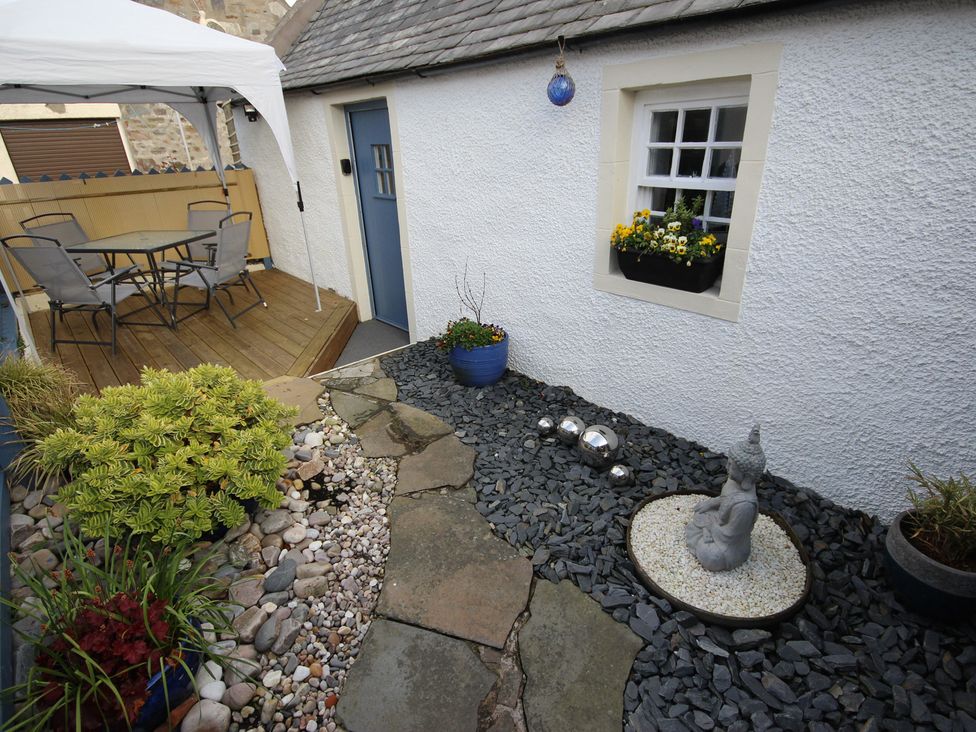 A garden with a table and chairs on a deck at Zen Cottage in Buckie