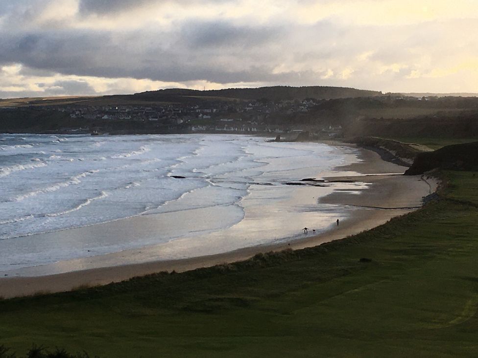 A beach with waves and people walking at Zen Cottage in Buckie