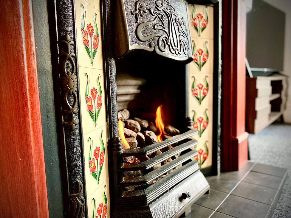A fireplace with decorative tiles and a fire at 1 Horncliffe Road Blackpool