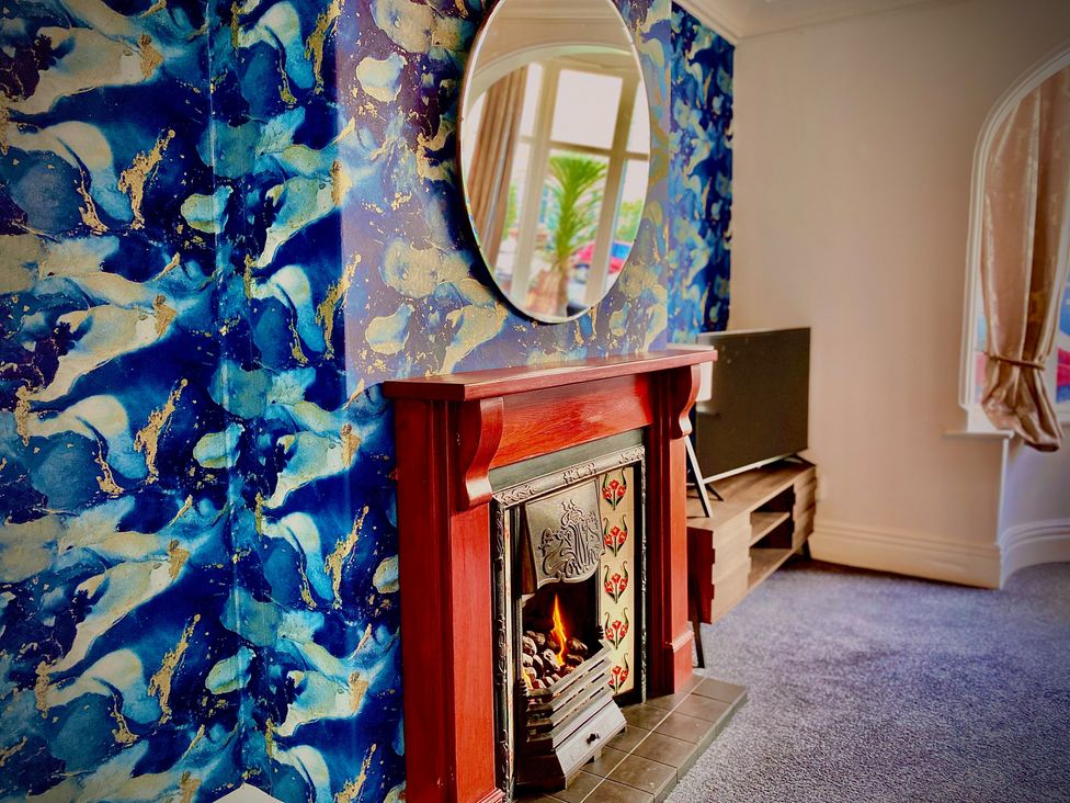 A living room with a fireplace and a mirror at 1 Horncliffe Road in Blackpool