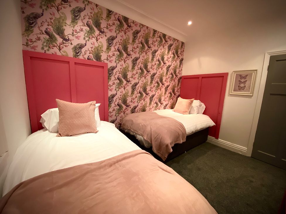 A bedroom with two beds and patterned wallpaper at 1 Horncliffe Road in Blackpool