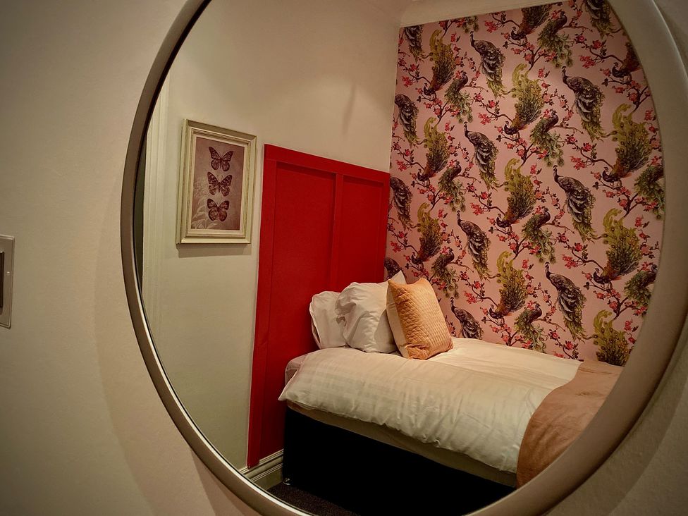 A bedroom with a bed and floral wallpaper at 1 Horncliffe Road in Blackpool