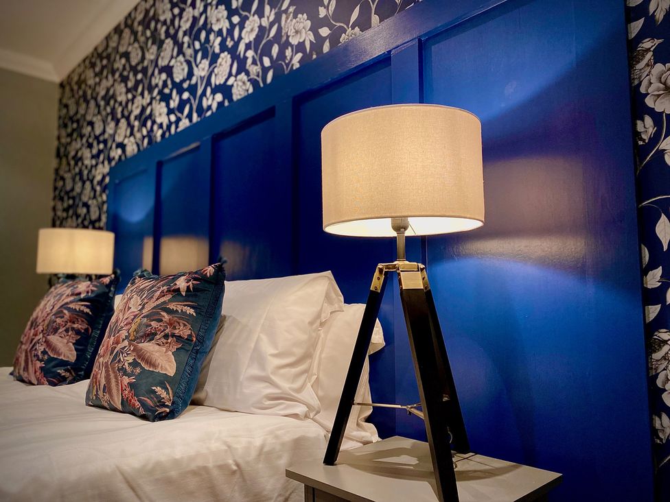 A bedroom with a blue headboard and lamps at 1 Horncliffe Road Blackpool