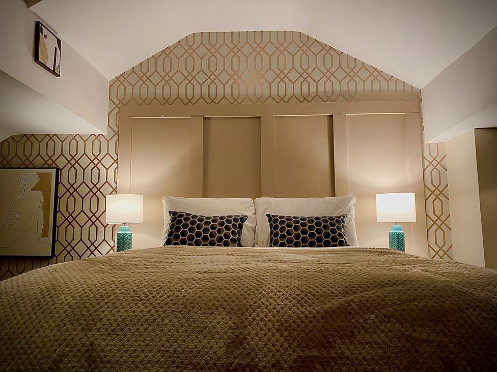 A bedroom with a bed, bedside tables and wall art at 1 Horncliffe Road in Blackpool