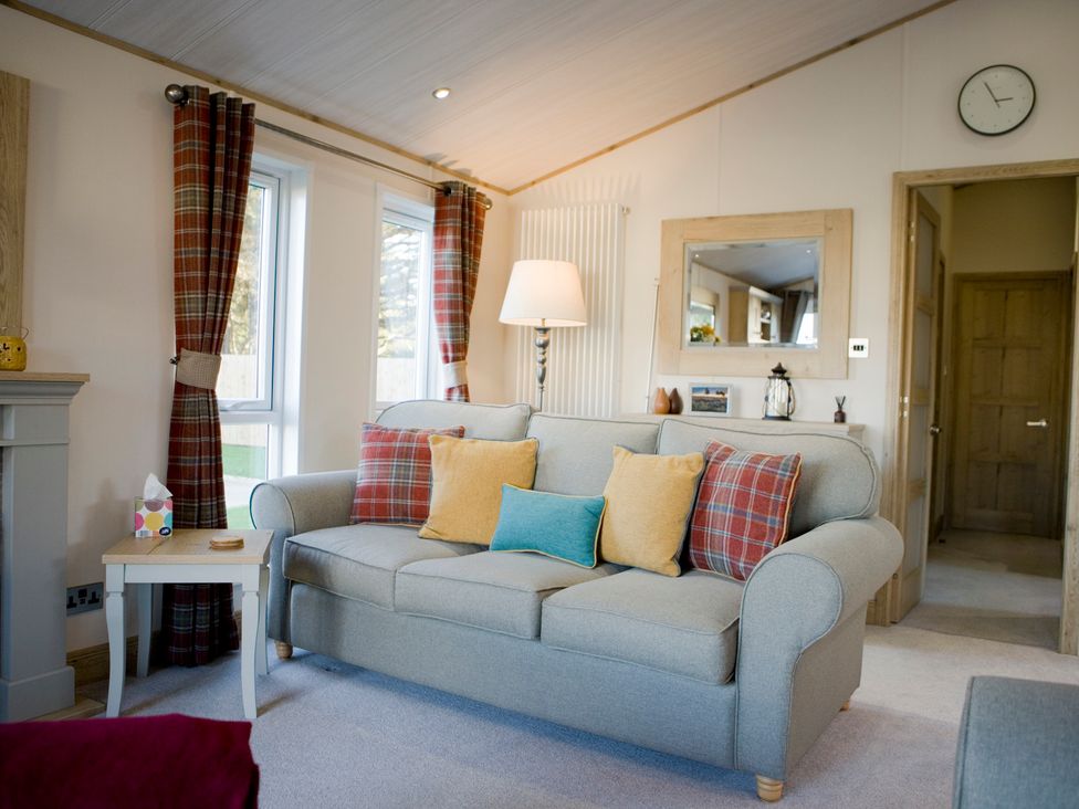 A living room with a sofa, lamp, and mirror at Orchid 9 in Christchurch