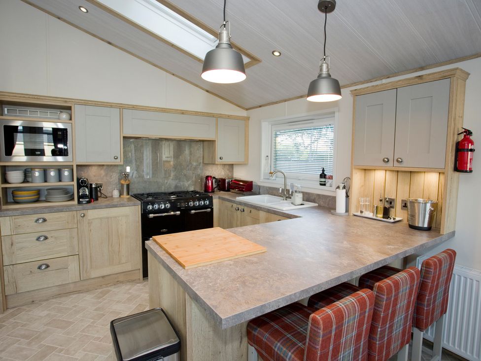 A kitchen with cabinets and a gas stove at Orchid 9 Christchurch