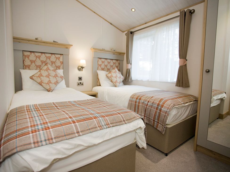 A bedroom with twin beds and a wardrobe at Orchid 9 in Christchurch