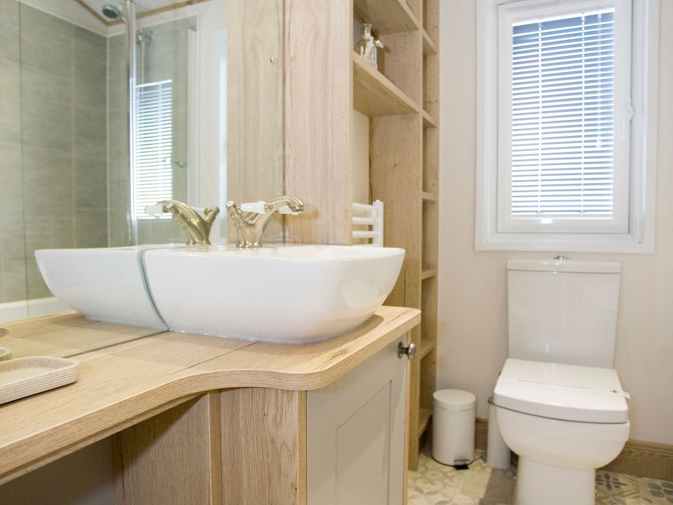 A bathroom with a sink, toilet and shelf at Orchid 9 Christchurch