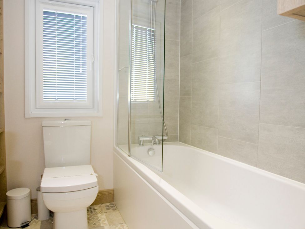 A bathroom with a bathtub and a toilet at Orchid 9 in Christchurch