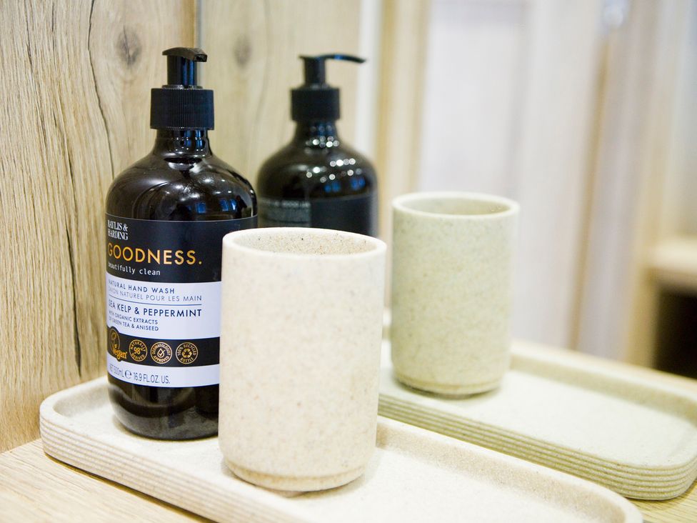 A hand wash bottle and cup on a tray in a bathroom at Orchid 9 Christchurch