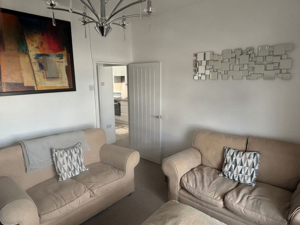 A living room with two sofas and a door at Penmaenmawr Coastal Retreat
