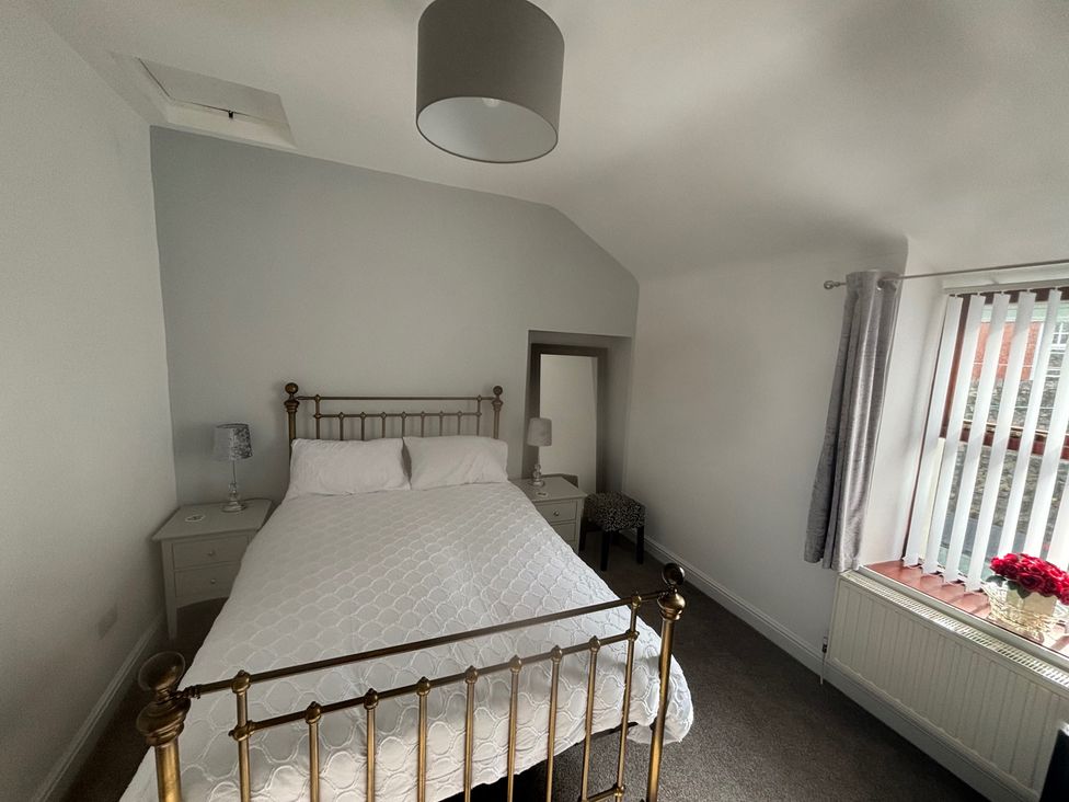 A bedroom with a bed, nightstand, and lamp at Penmaenmawr Coastal Retreat