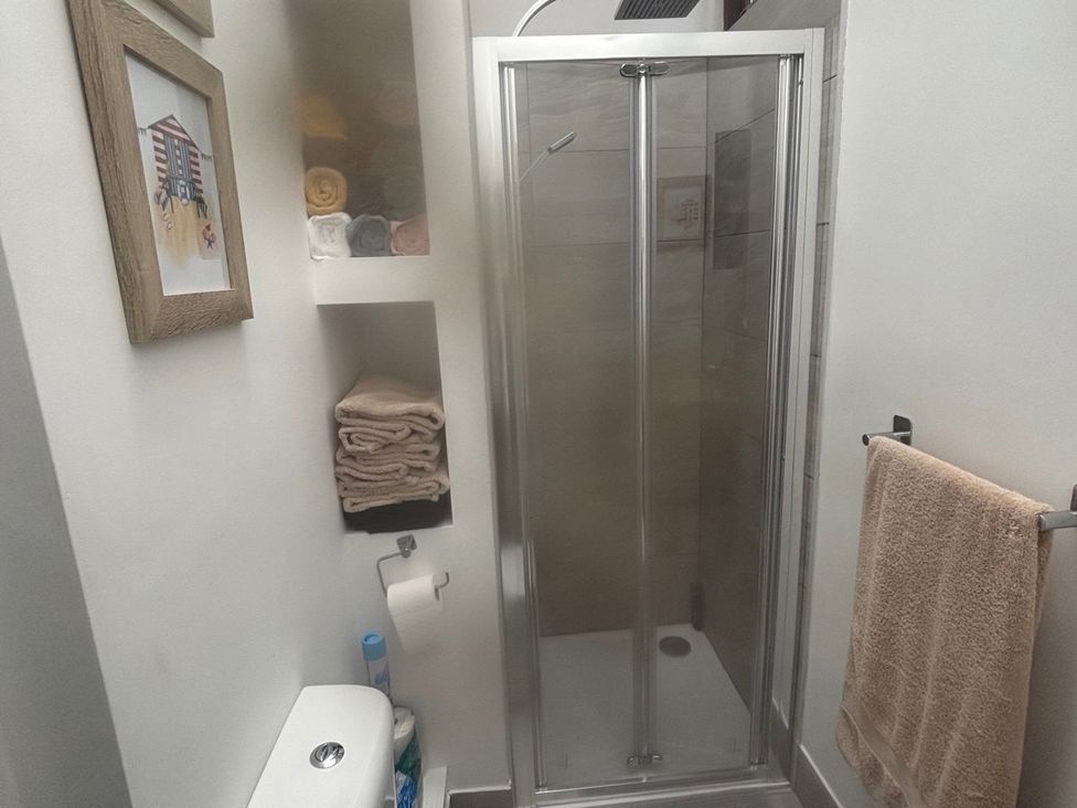 A bathroom with a shower and towels at Penmaenmawr Coastal Retreat