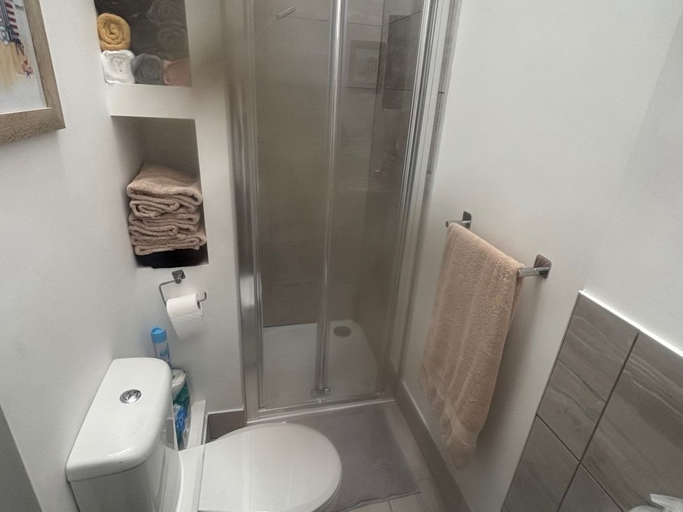 A bathroom with a shower, toilet, and towels at Penmaenmawr Coastal Retreat