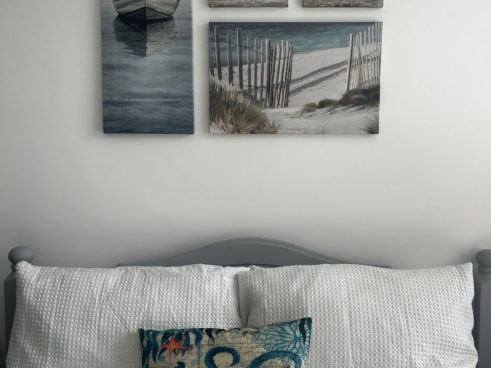 A bed with pillows and wall art at The Weymouth House in Weymouth