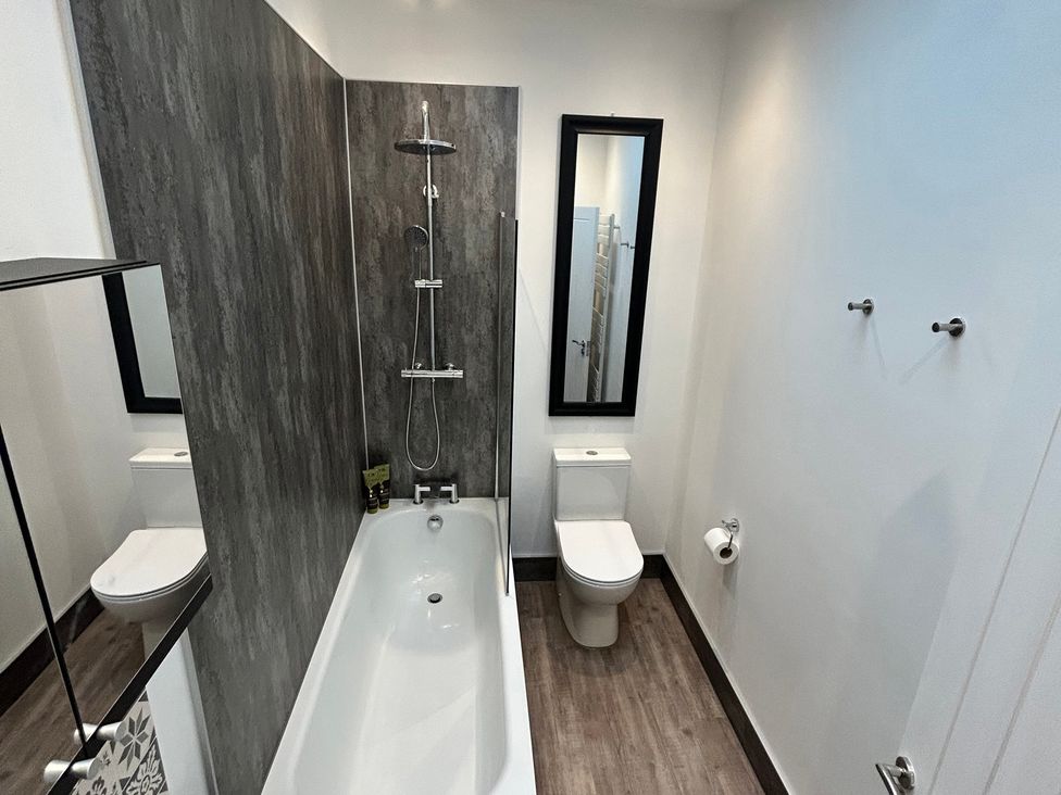 A bathroom with a bathtub and a toilet at The Weymouth House in Weymouth